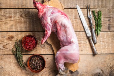 Çiğ yaban tavşanı, tahta tahtada otlu taze et. Ahşap arka plan. Üst görünüm.