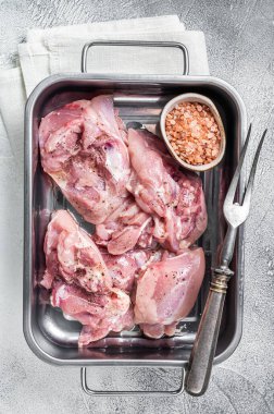 Cooking of Chicken leg thigh meat, Raw Boneless and skinless fillet in a steel tray. White background. Top view.