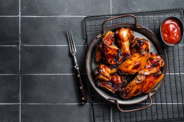 BBQ chicken wings in dip Barbecue sauce. Black background. Top view. Copy space.