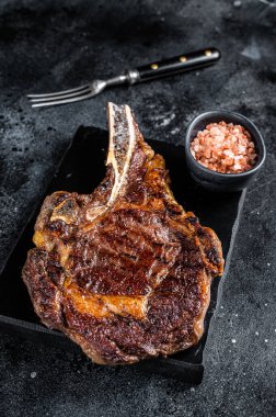 Grilled cowboy or rib eye with bone beef steak. Black background. Top view.