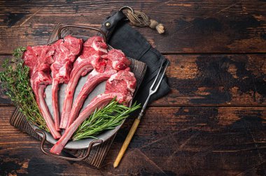 Fresh Raw Lamb chop steak in steel tray with herbs. Wooden background. Top view. Copy space.