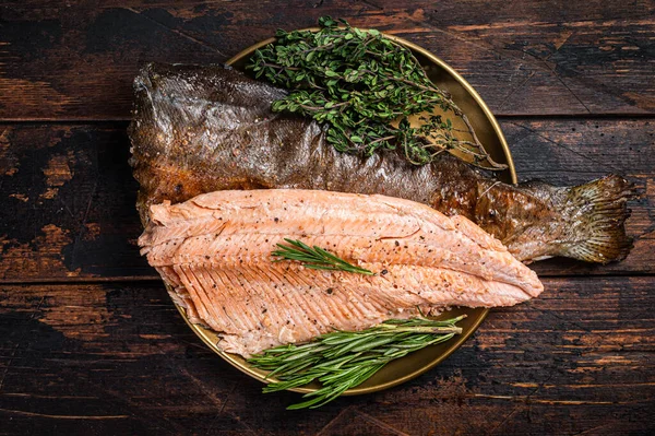 Baked Trout fillet, roasted fish on a plate with thyme and rosemary. Wooden background. Top view.