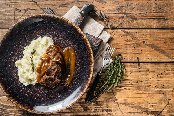 Beef cheeks stewed in red wine sauce with mashed potatoes. Wooden background. Top view. Copy space.