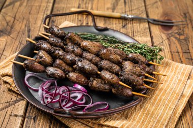 Churrasco Brazilian barbecue, chicken hearts grilled kebabs with herbs and vegetables. Wooden background. Top view.
