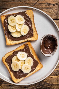 Çikolatalı, fındık ezmeli ve muzlu sandviç pişirmek. Ahşap arka plan. Üst görünüm.