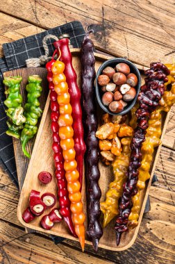 Colored Churchkhela Georgian sweets with Walnuts and hazelnuts. Wooden background. Top view.