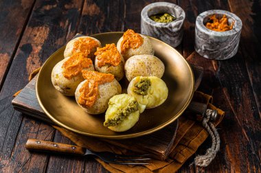 Canary Islands dish Papas Arrugadas wrinkly salty potatoes with and Mojo picon red spicy sauce. Wooden background. Top view.