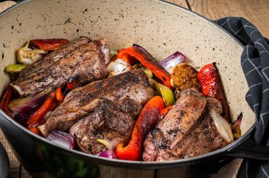 Roasted slow cooked lamb shanks with vegetables and herbs. Wooden background. Top view.