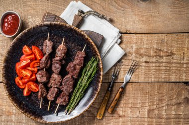 Izgara dana eti şiş kebap şiş şiş kebap ya da domatesli bir tabakta Şiş lik. Ahşap arka plan. Üst Manzara. Boşluğu kopyala.