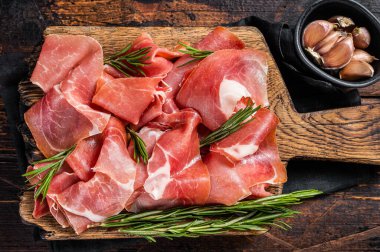 Jamon serrano jambonu dilimleri ya da ahşap tahtada biberiyeli prosciutto crudo parma. Ahşap arka plan. Üst görünüm.