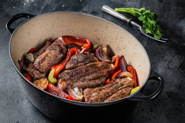 Braised slow cooked lamb shank in red wine sauce with vegetables in cooking pot. Black background. Top view.