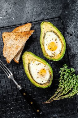 Cooking Baked Avocado with Egg. Black background. Top view.