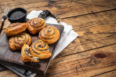 Poppy seed rolls and cardamom buns, Traditional Nordic baked sweet breads on wooden board. Wooden background. Top view. Copy space.