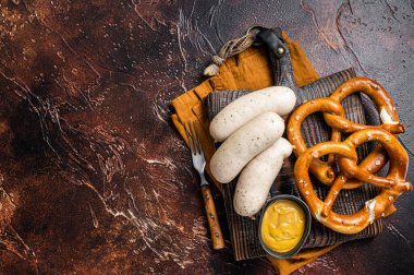 Traditional German pretzel with white sausage and mustard. Dark background. Top view. Copy space.