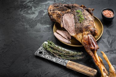 Christmas dish - Roast lamb leg meat with spices and thyme on a plate. Black background. Top view. Copy space.