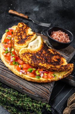 Doldurulmuş domatesli omlet, kırmızı dolma biber ve ahşap tahtada soğan. Siyah arka plan. Üst görünüm.