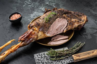 Christmas dish - Roast lamb leg meat with spices and thyme on a plate. Black background. Top view.