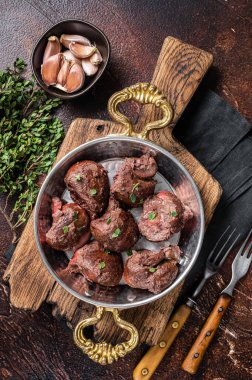 Kızarmış sığır böbreği, tavada sakatat eti ve şifalı otlar. Karanlık arka plan. Üst görünüm.