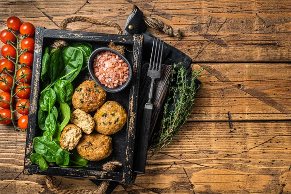 Seafood Fish balls or Fish cake with spinach and herbs in a tray. Wooden background. Top view. Copy space.