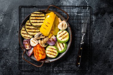 Grilled vegetables, bell pepper, zucchini, eggplant, onion and tomato. Black background. Top view.