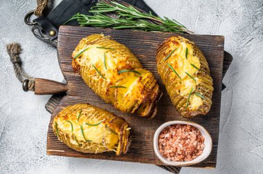 Roasted hasselback potatoes with cheese, garlic, thyme and rosemary. White background. Top view.