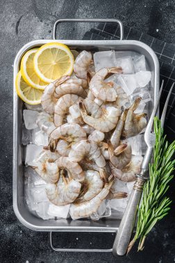 Kuyruğu buzda soyulmuş çiğ Pasifik beyaz karidesi. Siyah arka plan. Üst görünüm.