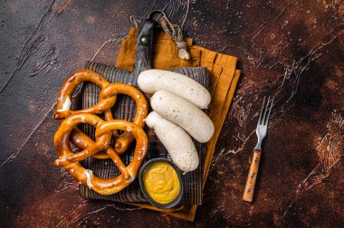 Traditional German pretzel with white sausage and mustard. Dark background. Top view.