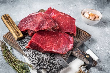 Raw Venison dear meat on butcher cutting board, game meat. Gray background. Top view.