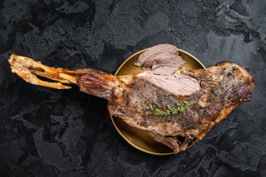 Christmas dish - Roast lamb leg meat with spices and thyme on a plate. Black background. Top view.