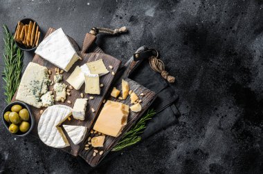 Delicious Cheese board. Assortment of cheese, camembert, brie, Gorgonzola, parmesan, olives, nuts and herbs. Black background. Top view. Copy space.