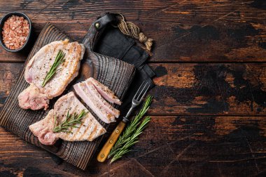 BBQ grilled pork chop steaks or cutlets sliced on wooden cutting board. Wooden background. Top view. Copy space.