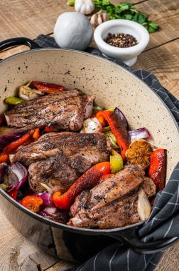 Roasted slow cooked lamb shanks with vegetables and herbs. Wooden background. Top view.