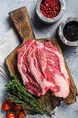 Tahta bir tahtanın üzerinde kekik ile çiğ Chuck Roll biftekleri. Gri arka plan. Üst görünüm.