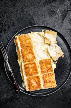 Turkish Su Boregi pie, Tabla borek or burek in plate. Black background. Top view.