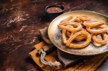 Spanish dessert churros with hot spicy chocolate. Dark background. Top view. Copy space.