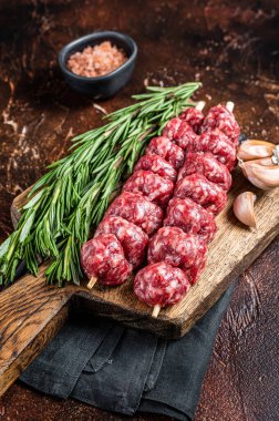 Raw traditional shish kebab Skewers with beef meat ans spices. Dark background. Top view.