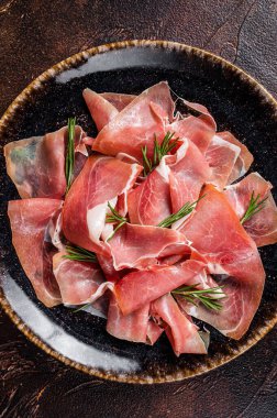 Bir dilim prosciutto crudo parma ya da jamon serrano ve biberiye. Karanlık arka plan. Üst görünüm.