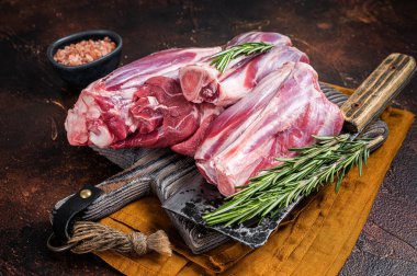 Uncooked Raw lamb mutton shanks on a butcher board. Dark background. Top view.