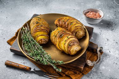 Baked Hasselback Potato with Fresh thyme and rosemary. Gray background. Top view.