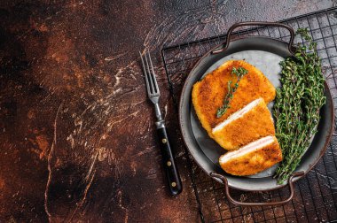 Cordon bleu chicken fillet cutlet with ham and cheese. Dark background. Top view. Copy space.