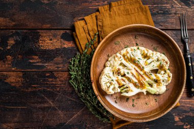 Grilled Cauliflower steaks with a cilantro lime chimichurri sauce, Plant based meat substitute concept. Wooden background. Top view. Copy space.