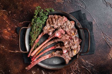 BBQ Grilled lamb chop steak, mutton rib cutlet in steel tray with thyme. Dark background. Top view.