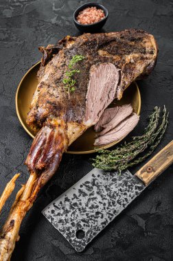 Christmas dish - Roast lamb leg meat with spices and thyme on a plate. Black background. Top view.