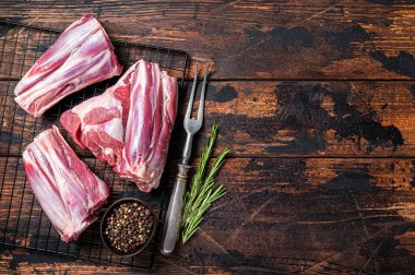Raw lamb shanks with herbs and spices ready for cooking. Wooden background. Top view. Copy space.