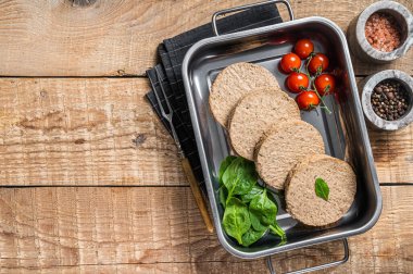 Bitki temelli etten yapılmış çiğ et köfteleri mutfak tepsisinde otlu taze vegan burger pirzolası. Ahşap arka plan. Üst Manzara. Boşluğu kopyala.