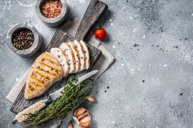 Kesme tahtasında dilimlenmiş hindi ızgara göğüs bifteği. Gri arka plan. Üst Manzara. Boşluğu kopyala.