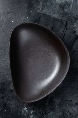 Masada boş siyah bir tabak var. Masa ayarı. Siyah arka plan. Üst Manzara. Boşluğu kopyala.