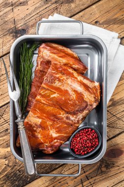 American Smoked Pork spare Ribs in steel tray with herbs. Wooden background. Top view.