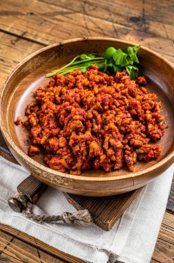 Traditional italian tomato sauce bolognese with minced meat in a wooden plate with herbs. Wooden background. Top view.
