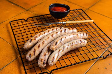 Grilled pork sausages from a BBQ. Orange background. Top view.